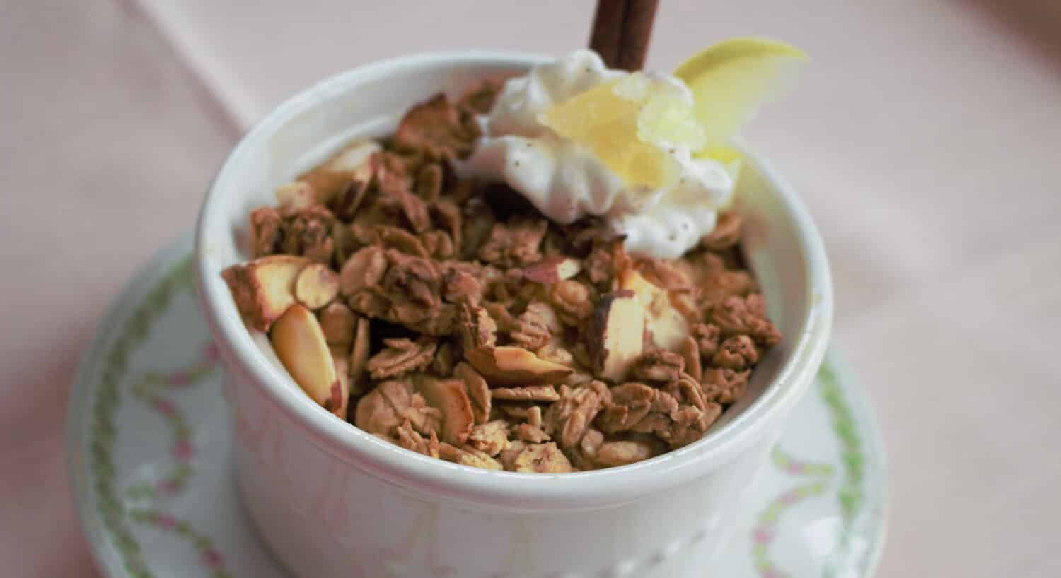 Home made granola in a white bowl with cream on top