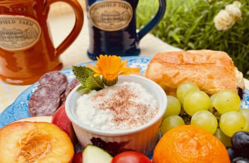 Blue page holding assortment of fresh fruits, cut meet and danish along with cottage cheese, coffee mugs with Smithfield Farm emblem