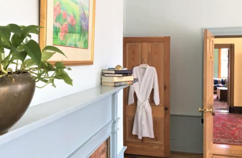 Fireplace mantel of grey panyed wood and door with a fluffy white robe