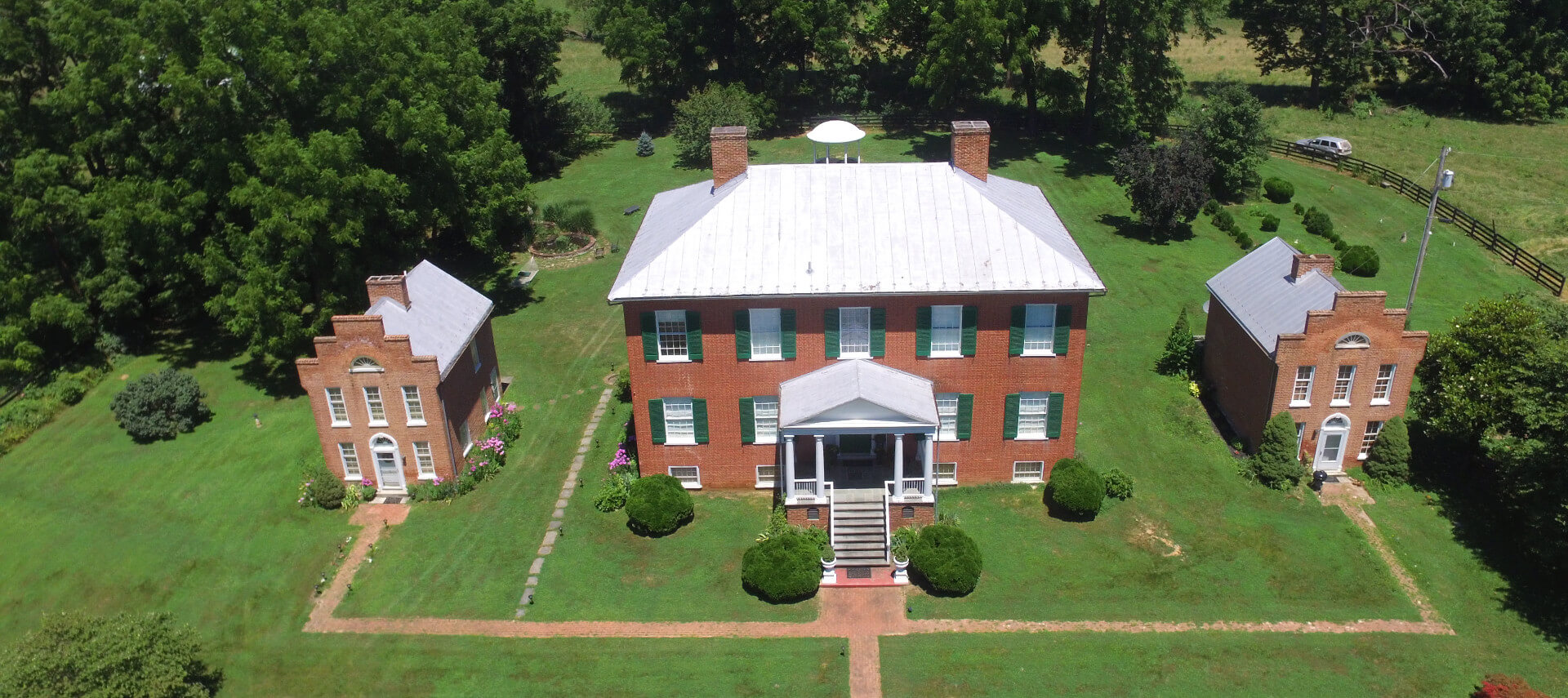 Large brick manor house with green shutters and expansive lawns